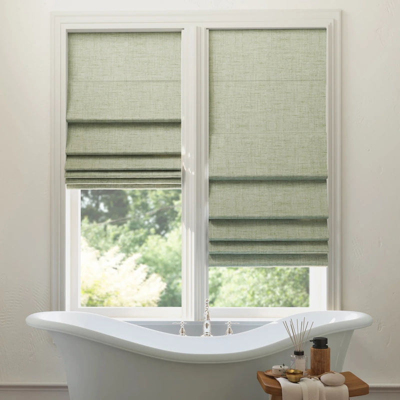 Sage green Roman shades over a white bathtub