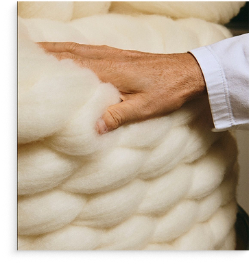 Close-up of hand touching soft, white wool fibers