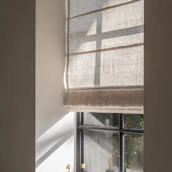 Linen roman blinds filtering sunlight on a white wall